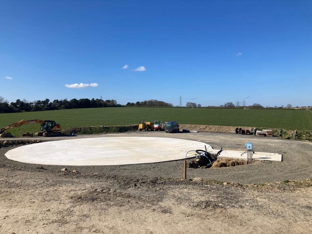 Wide view of a prepared concrete pad with groundworks machinery on site